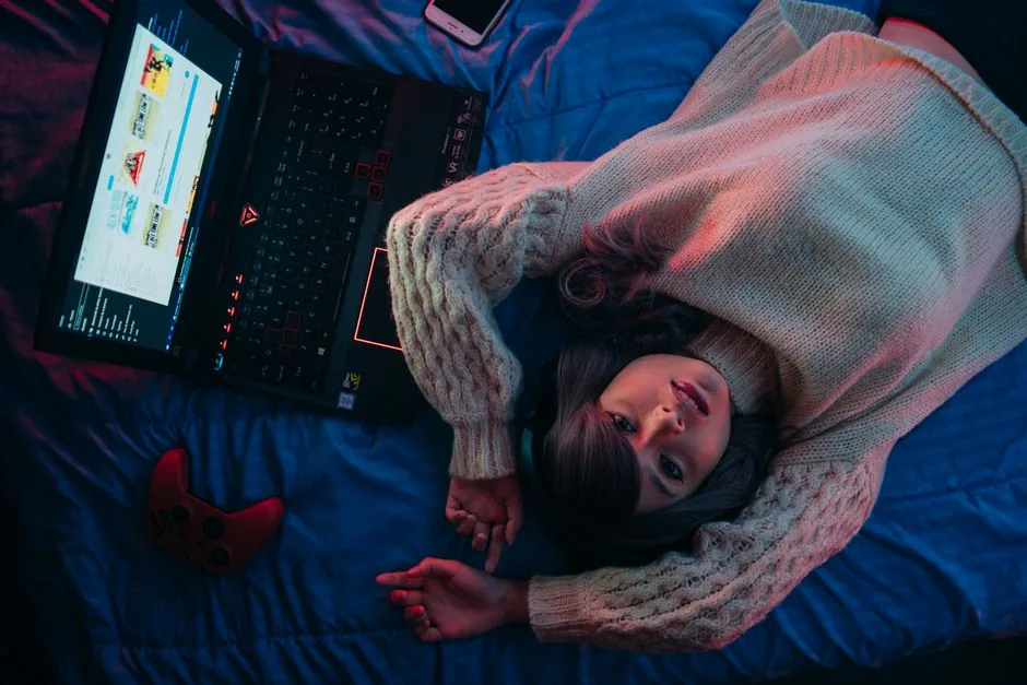 gamer playing on a laptop with a controller in bed for lifestyle gaming