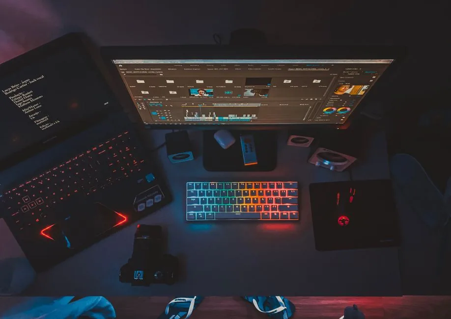 A video editing timeline with color scopes and a rendering queue on a dual monitor setup