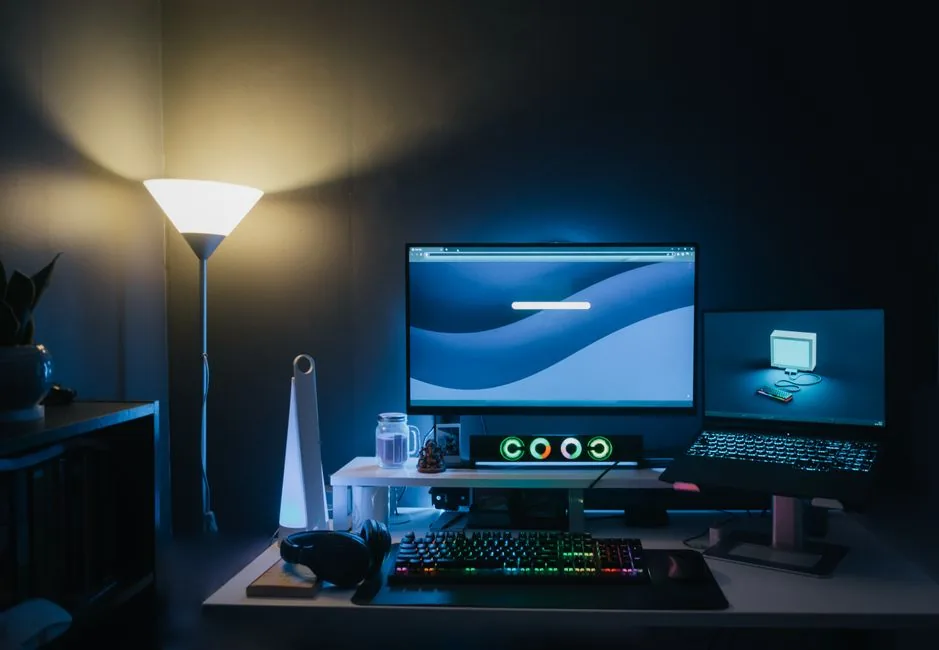 A desk setup at night with a light bar illuminating the keyboard area without glare